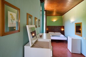 A room with a bed, a desk with a mirror, framed pictures, a small table, and a refrigerator. - Room 'Santa Lorica - Camera 12' with Shared Pool, Shared Garden and Wi-Fi (Sassetta)