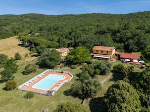 Vue aérienne d’une propriété comprenant une piscine, plusieurs bâtiments et une végétation luxuriante.