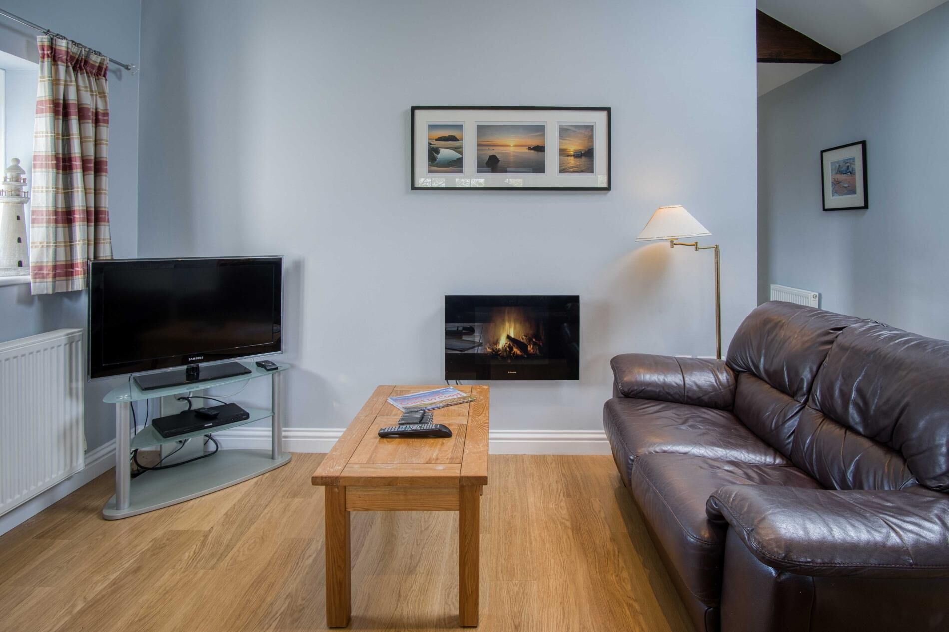 A living room with a flat-screen TV, a fireplace, a leather sofa, and a wooden coffee table.