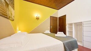 A hotel room with a bed, a nightstand, a wall-mounted light, a wardrobe, and a door. - Room 'Santa Lorica - Camera 14' with Shared Pool, Shared Garden and Wi-Fi (Sassetta)