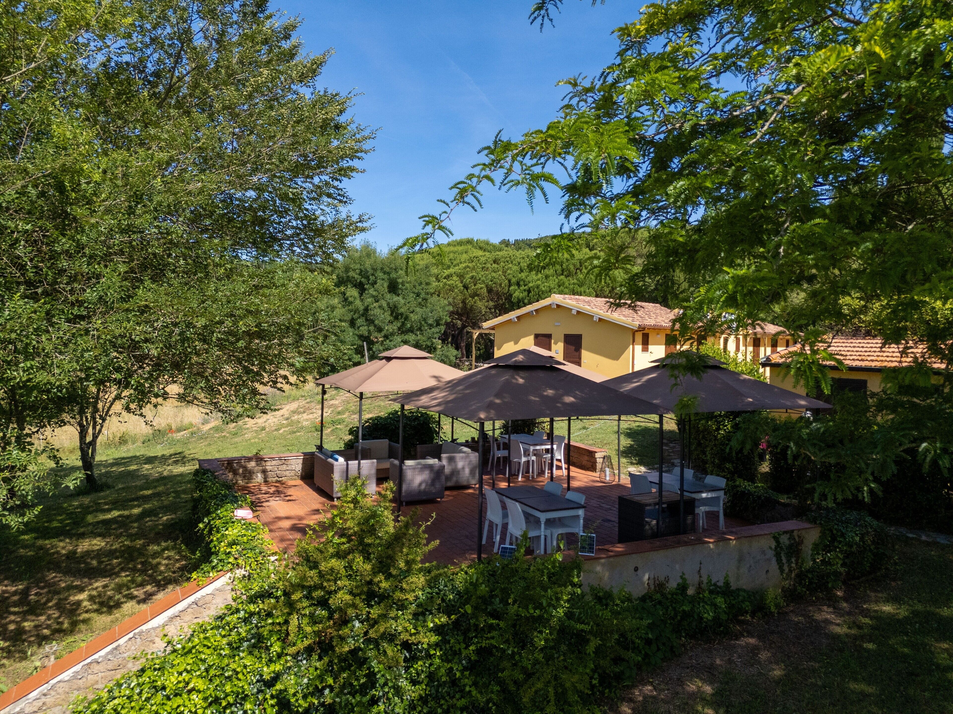 A patio area with outdoor furniture, a covered seating area, and a house in the background.