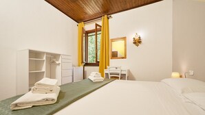 A hotel room with a bed, a desk, a wardrobe, and a window with curtains. - Room 'Santa Lorica - Camera 14' with Shared Pool, Shared Garden and Wi-Fi (Sassetta)