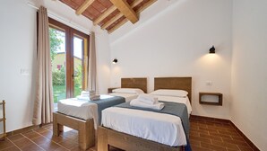 A room with two beds, wooden beams on the ceiling, a window with curtains, and a small shelf. - Room 'Santa Lorica - Camera 20' with Shared Pool, Wi-Fi and Air Conditioning (Sassetta)