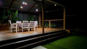 An outdoor deck with a table and chairs, surrounded by greenery. - The Residence- A home away from home. Pet friendly/ family friendly. (Jindalee)