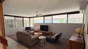 A modern living room with a sectional sofa, a TV, and a coffee table. - The Residence- A home away from home. Pet friendly/ family friendly. (Jindalee)