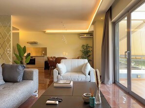 A modern living room with a sofa, coffee table, and a dining area in the background. - Luxurious & Spacious Flat in Glyfada Center (Glifada)