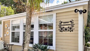 Uma pensão com fachada bege, janelas emolduradas em branco e uma placa com o texto 'Harper's Guesthouse'.