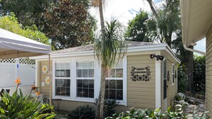 Um pequeno edifício térreo com fachada bege, janelas emolduradas por branco e uma placa com a inscrição 'Harper's Guesthouse'.