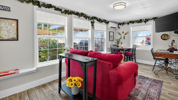 Uma sala de estar moderna com um sofá vermelho, uma mesa de jantar e grandes janelas com vista para o exterior.