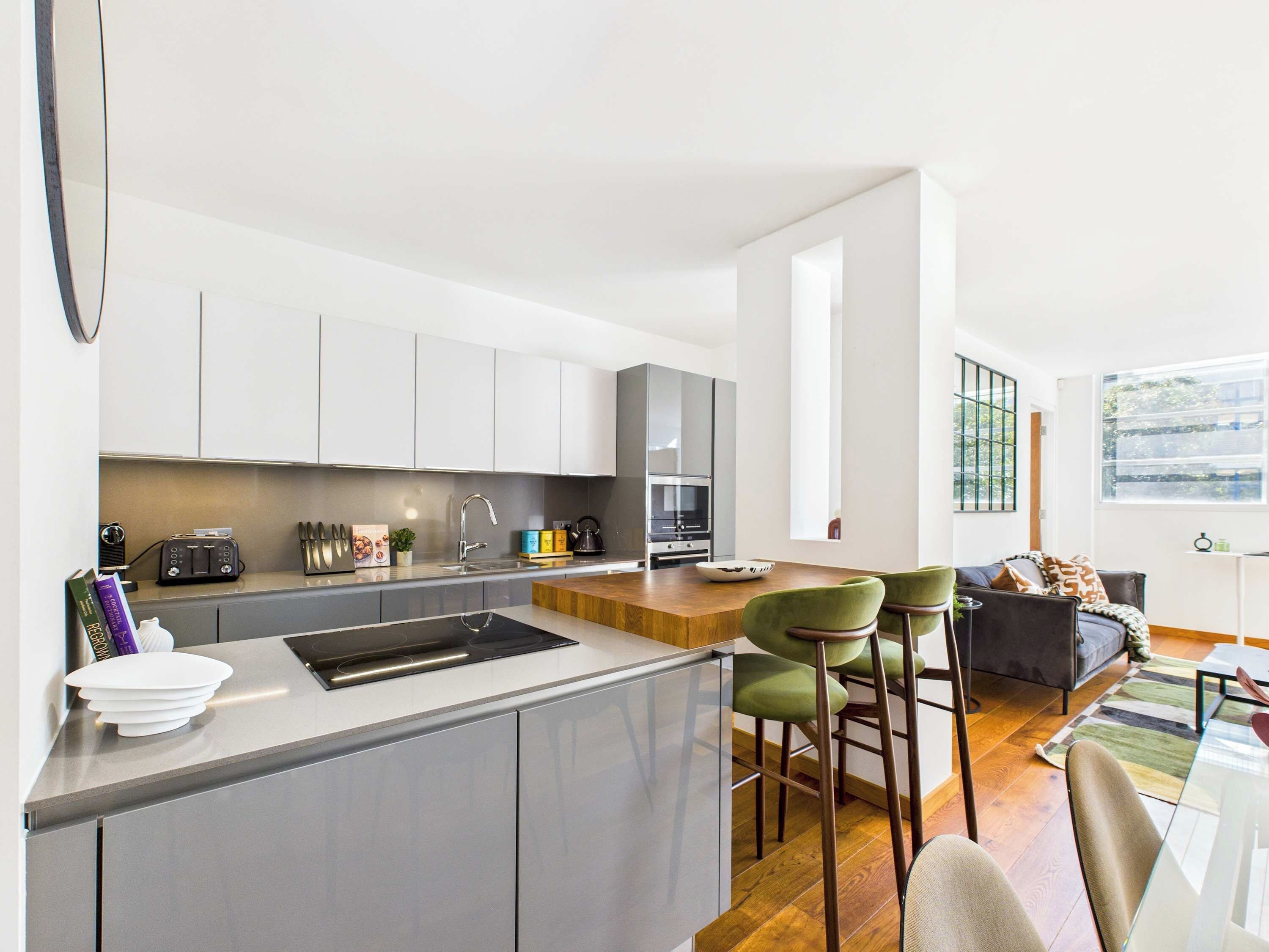 Una cocina moderna con una isla central, electrodomésticos integrados y una zona de comedor con taburetes de bar.