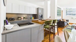 Una cocina moderna con una isla central, electrodomésticos integrados y una zona de comedor con taburetes de bar.