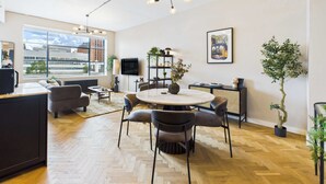 Un salon moderne avec une table ronde, des canapés et une grande fenêtre donnant sur la ville.
