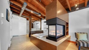 A modern interior with a fireplace, a bathtub, and a striped chair. - Mariner's Loft (Salt Spring Island)
