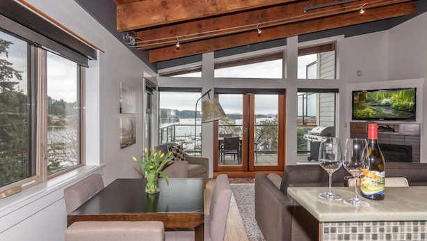 A modern interior with a dining area, seating, and a TV. - Mariner's Loft (Salt Spring Island)