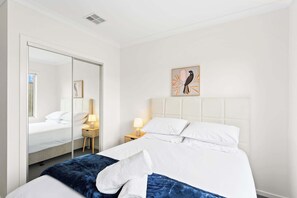 Camera d'albergo con un letto grande, un armadio, un comodino con una lampada e un quadro appeso al muro raffigurante un uccello.