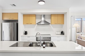 A modern kitchen with white cabinetry, stainless steel appliances, and a central island with a sink.