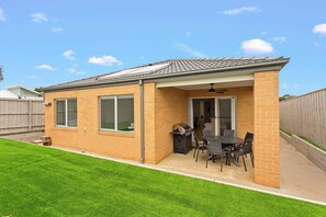 Une petite maison en briques avec un patio, une porte-fenêtre coulissante et un barbecue.