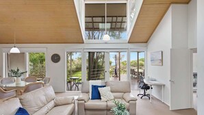 A spacious living area with a high ceiling, large windows, and a view of the outdoors. - Private Access to Beach, Oceanview with Home Gym (Silverleaves)