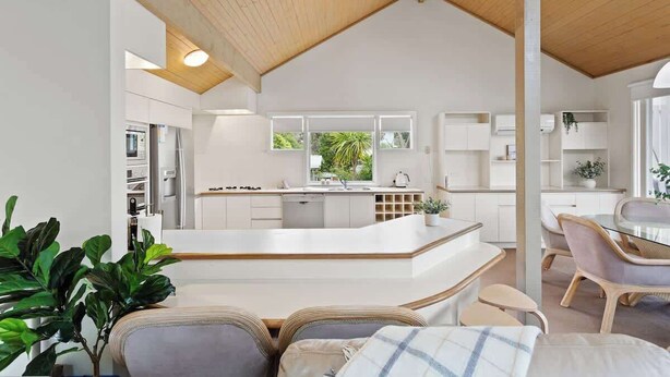A modern kitchen with a central island, white cabinetry, and a view of greenery outside. - Private Access to Beach, Oceanview with Home Gym (Silverleaves)