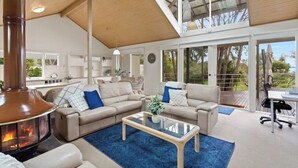 A spacious living area with a fireplace, two sofas, a coffee table, and a view of the outdoors. - Private Access to Beach, Oceanview with Home Gym (Silverleaves)