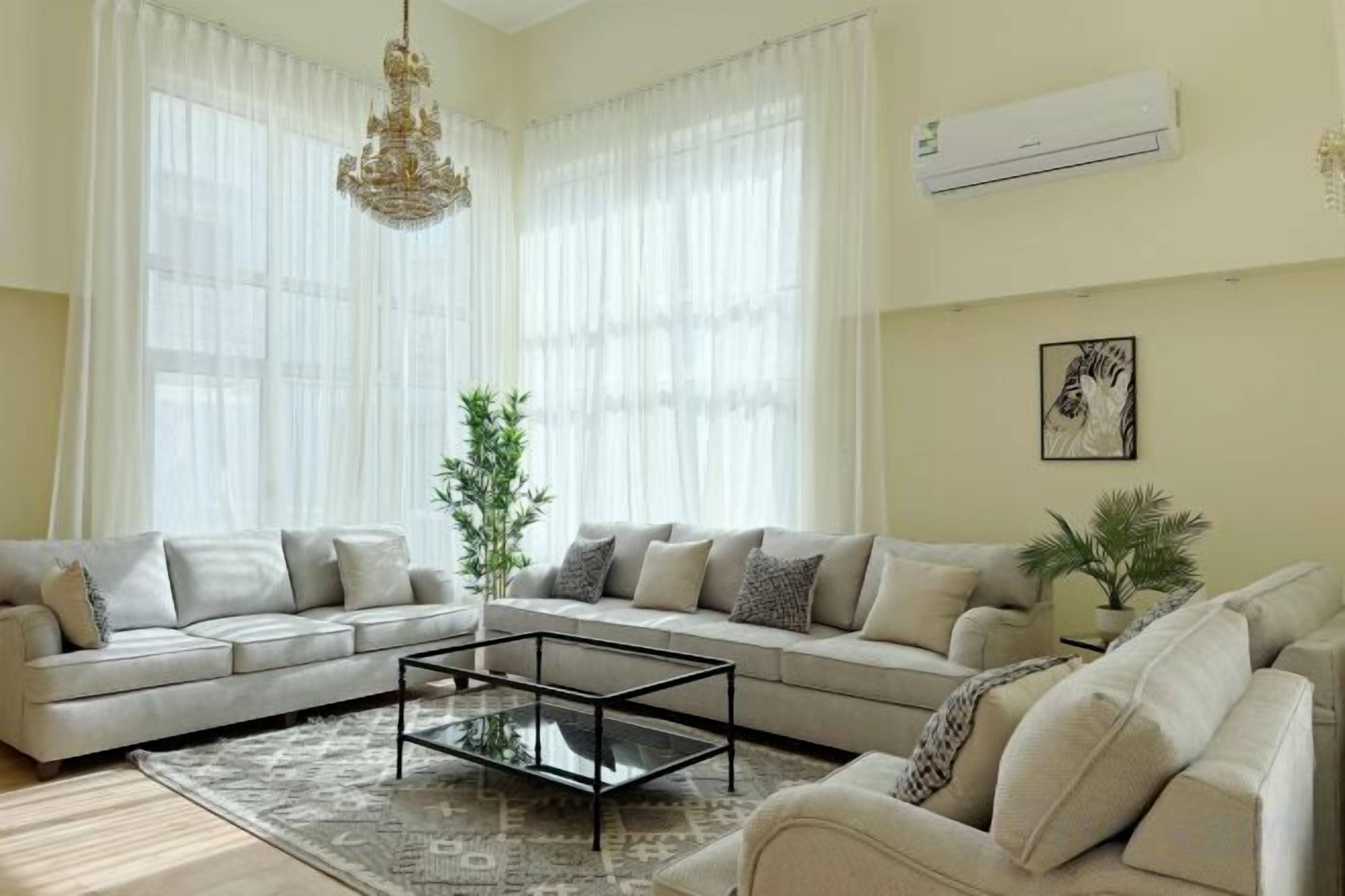 A living room with a sectional sofa, a glass coffee table, and a chandelier.