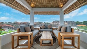 Un espace extérieur aménagé, abrité et doté de canapés et de tables, offrant une vue sur le paysage urbain.