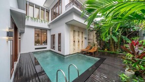 Une maison moderne dotée d’une piscine, d’une terrasse en bois et d’une végétation luxuriante.