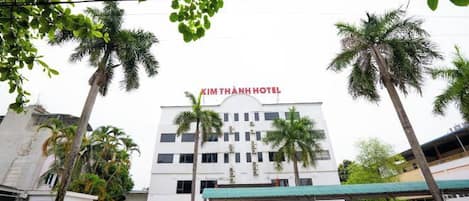 A building with a sign reading 'Kim Thanh Hotel' and palm trees in the foreground.
