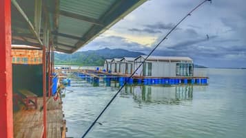 Propiedad frente al agua con muelle, cañas de pescar y un edificio con techo de metal.