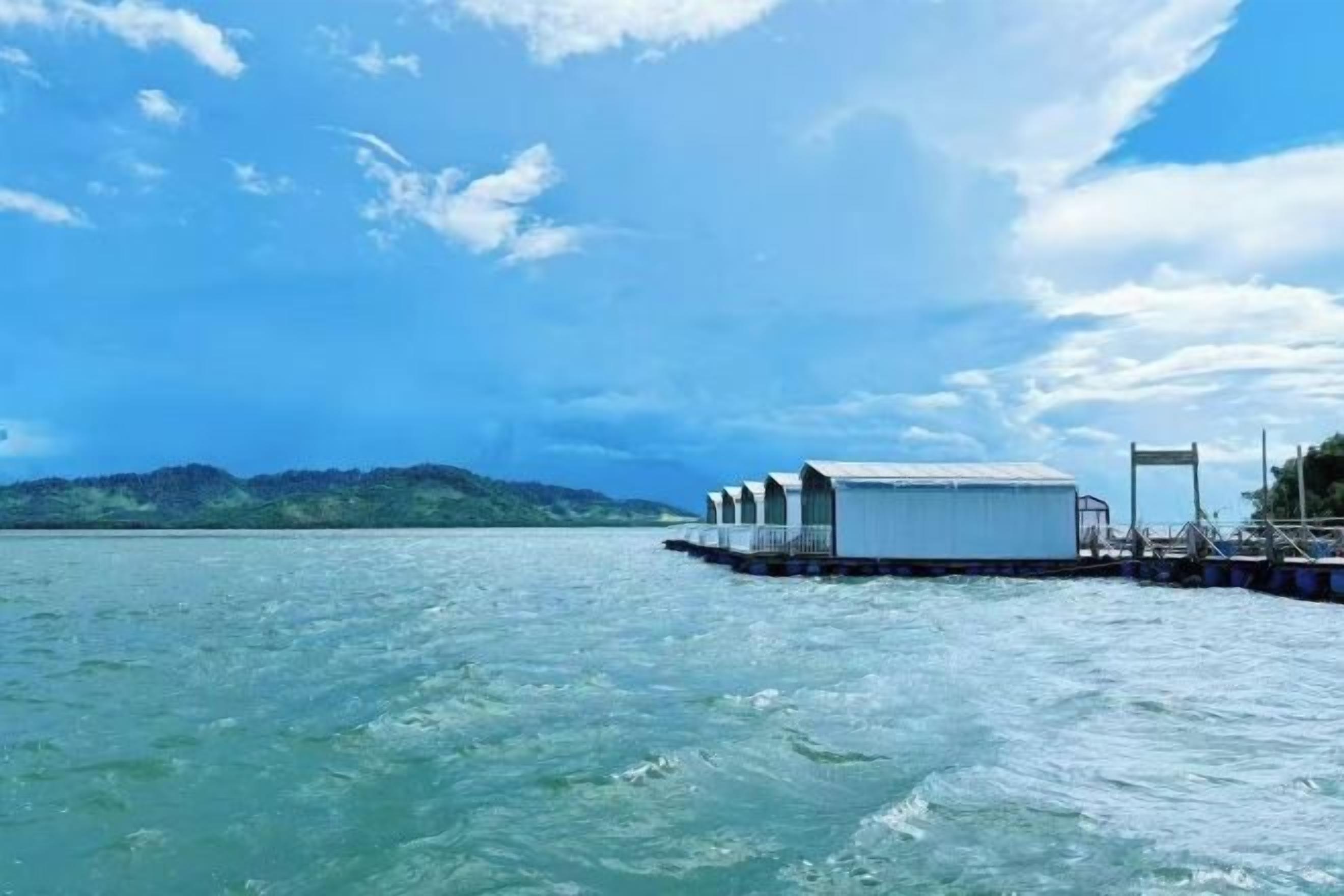 Una estructura flotante con varias habitaciones sobre el agua, conectada por un embarcadero.