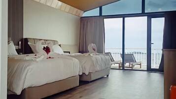 Habitación de hotel con dos camas, un ventanal grande y un balcón con una silla.
