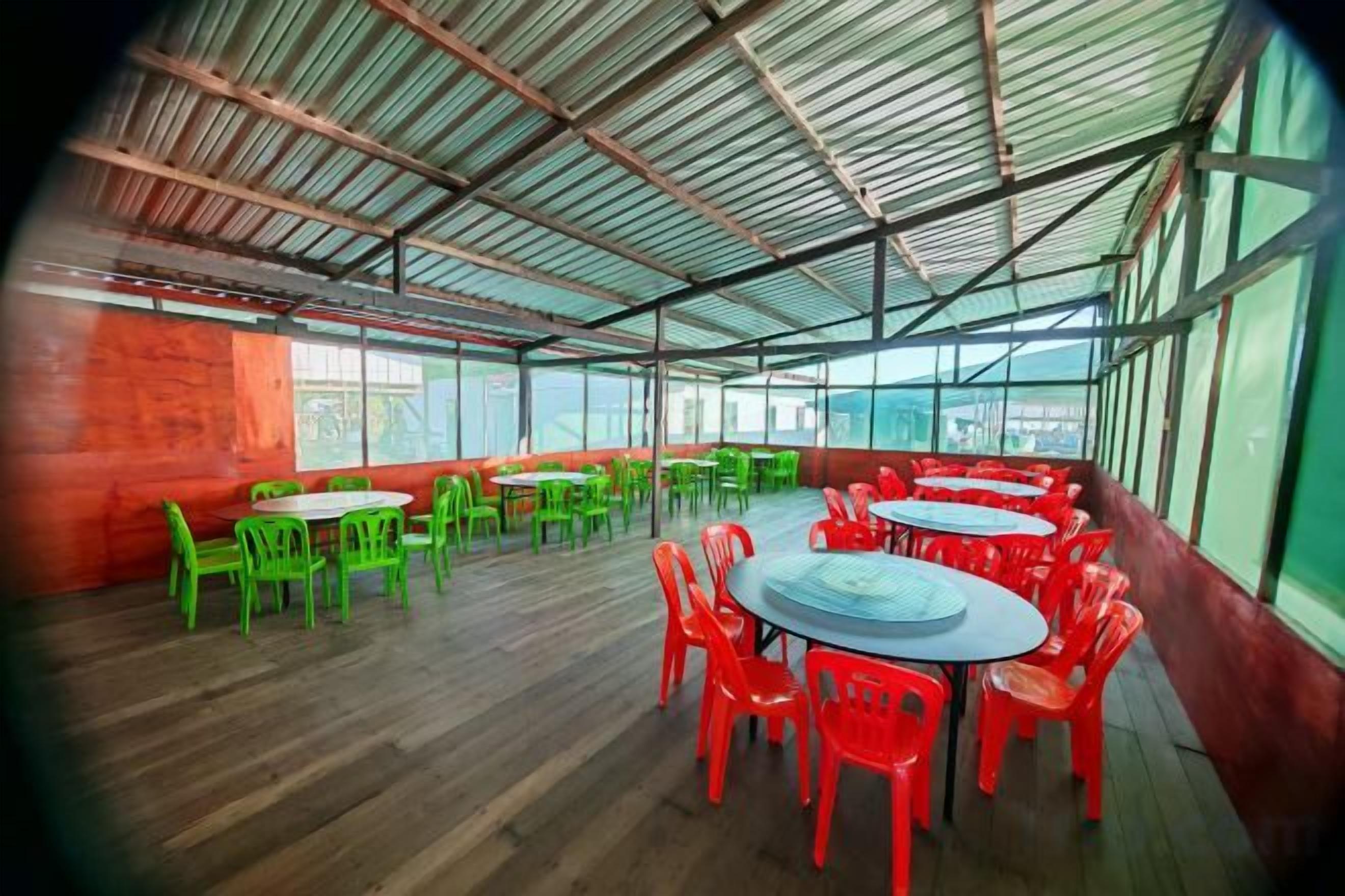 Un vaste espace intérieur doté de plusieurs tables et chaises rondes, de grandes fenêtres et d’un plafond haut.