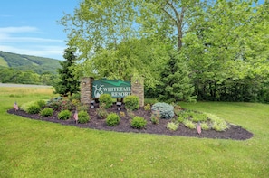 A sign for Whitetail Resort surrounded by landscaped garden beds and trees.