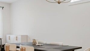 Ein stilvoller Essbereich mit einem schwarzen Tisch, weißen Stühlen und einer Kronleuchter.