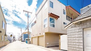 Une rue résidentielle bordée de maisons, avec un ciel dégagé et des lignes électriques visibles.