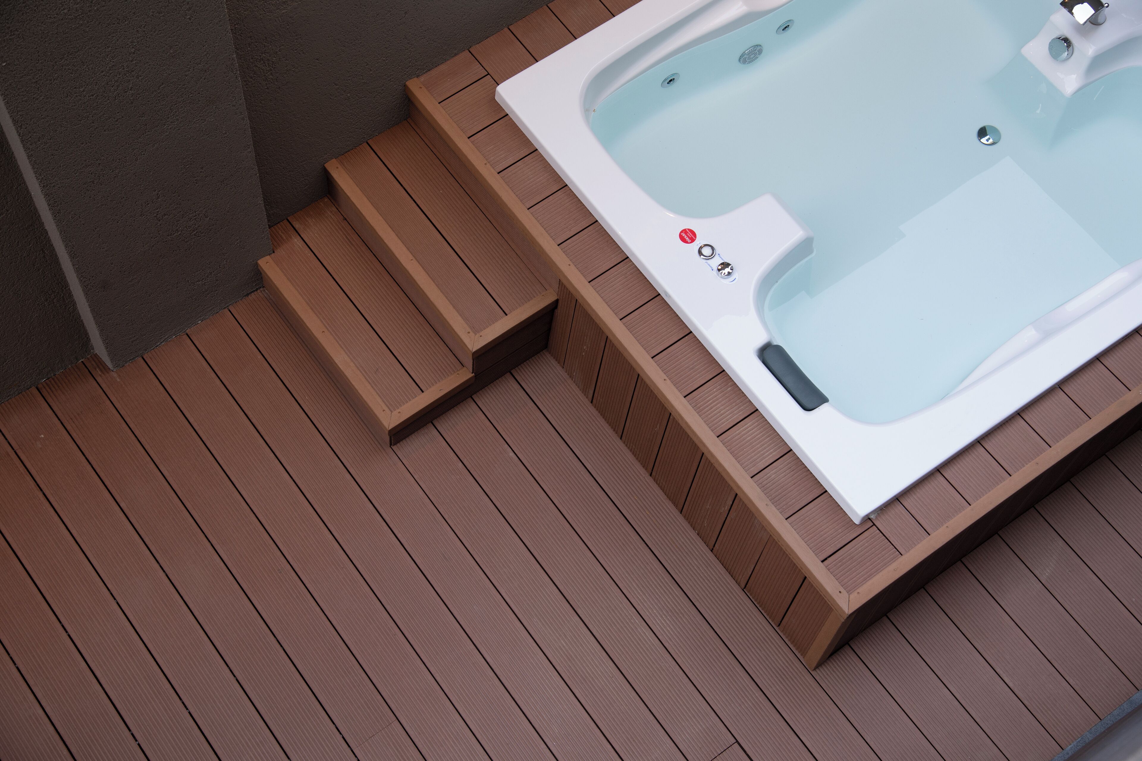 Un jacuzzi con escalones que lo rodean, en un deck de madera.