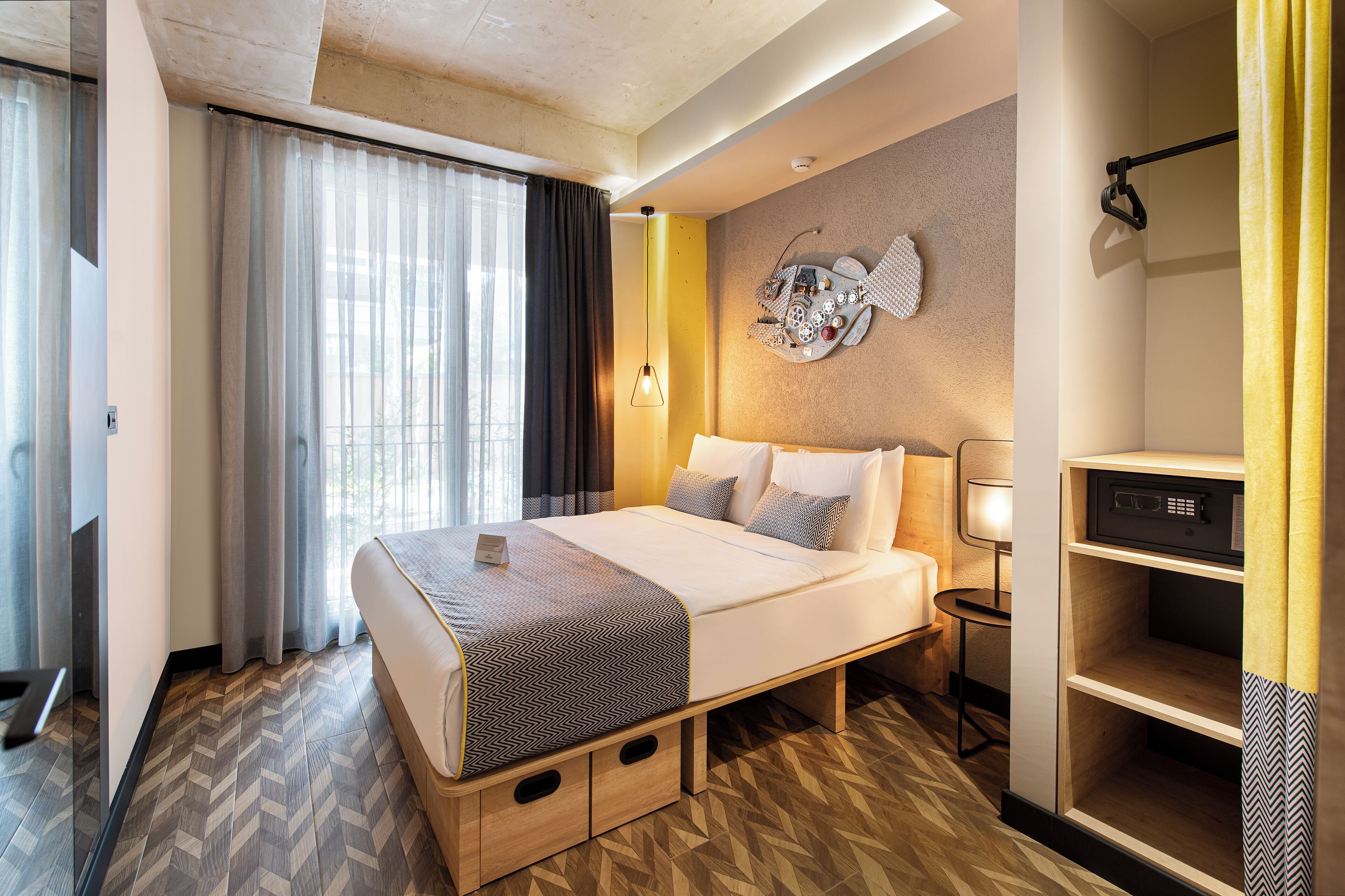 A hotel room with a bed, a desk, a lamp, and a wall decoration.