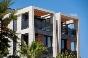 Um edifício moderno de vários andares com varandas, janelas amplas e uma combinação de painéis de concreto e madeira.