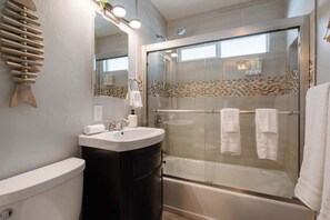 Une salle de bain moderne équipée de toilettes, d’un lavabo et d’une douche à parois de verre.