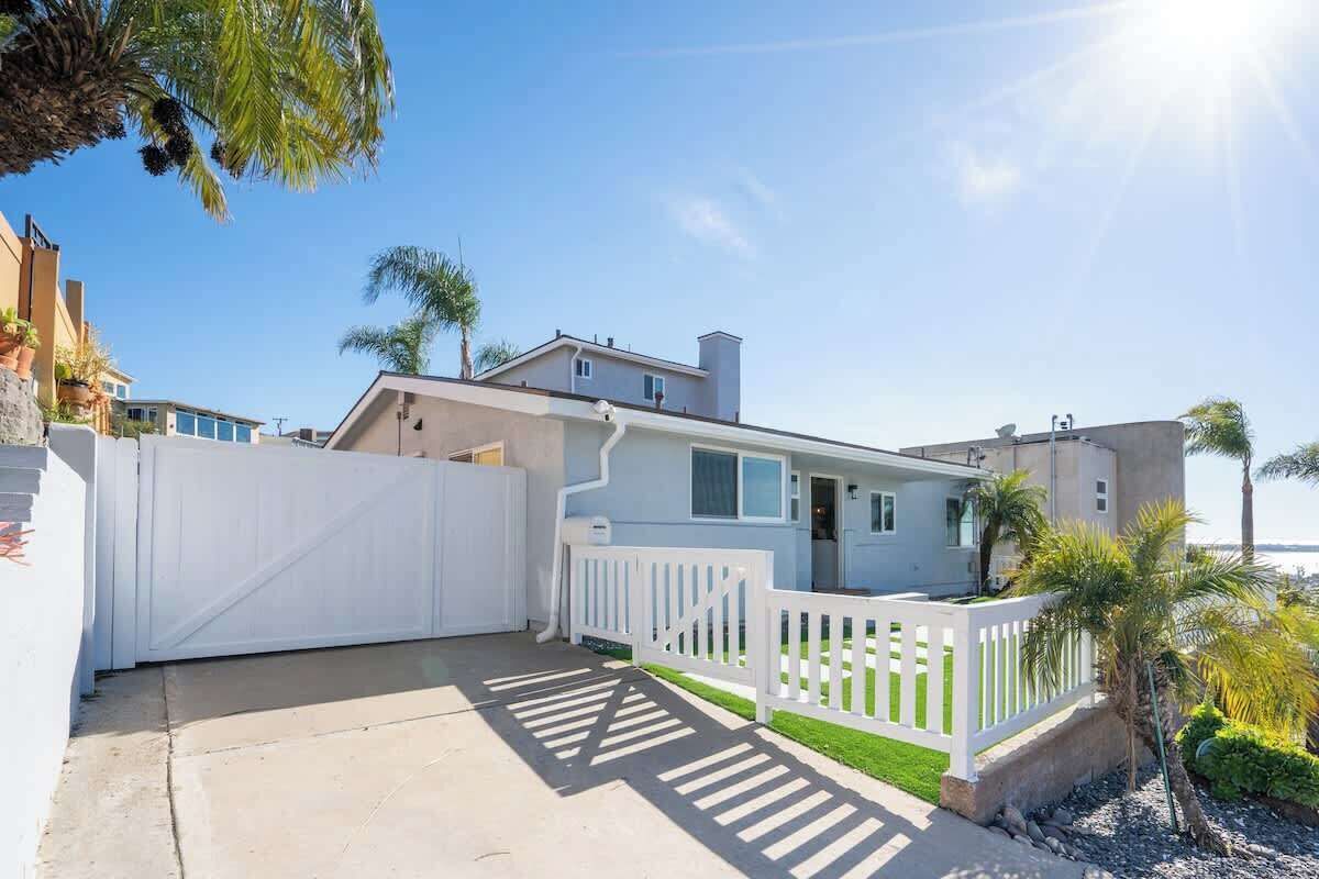 Une maison située sur la côte, avec une clôture blanche, un garage et une vue sur la mer.