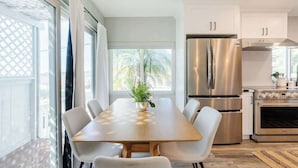 Une cuisine moderne dotée d’un grand îlot central, d’appareils électroménagers en acier inoxydable et offrant une vue sur les palmiers.