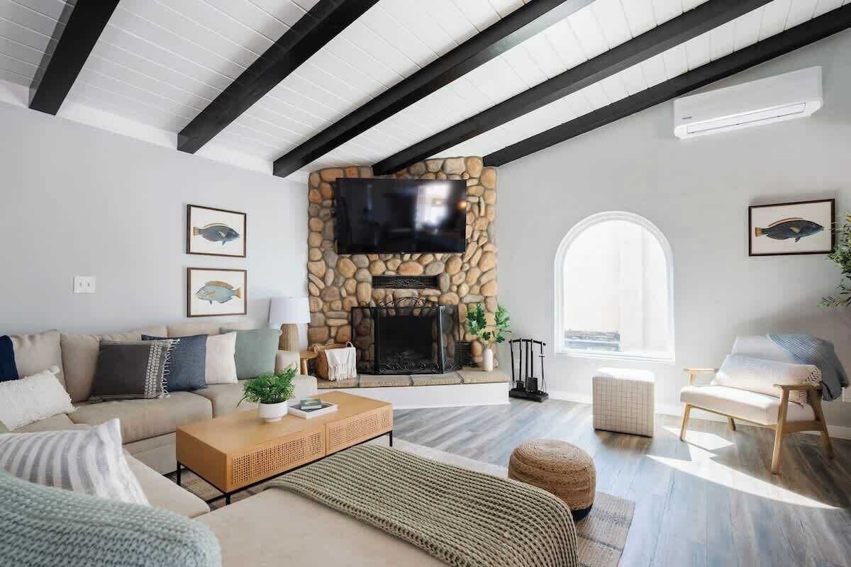 A living room with a stone fireplace, a sofa, a coffee table, and a TV mounted on the wall.