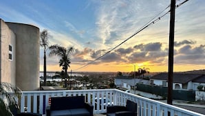 Un balcon avec des meubles d’extérieur, une vue sur la ville et un coucher de soleil.