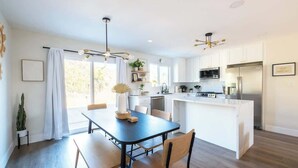 A modern kitchen with white cabinets, a central island, and a dining area with a table and chairs.