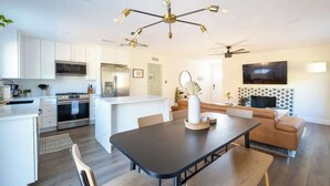 A modern kitchen with white cabinets, a central island, and a dining area with a dark table.
