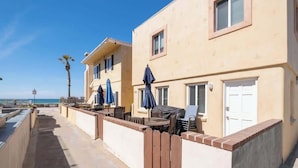 A seaside hotel with outdoor seating, a palm tree, and a view of the ocean. - Sunny 3BR Seaside Escape | Beach & Bay Steps Away! (San Diego)