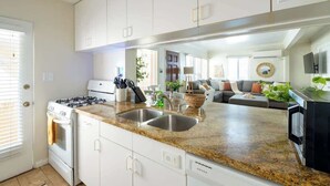 Cozinha moderna com armários brancos, bancadas de granito e eletrodomésticos de aço inoxidável, incluindo um forno embutido.