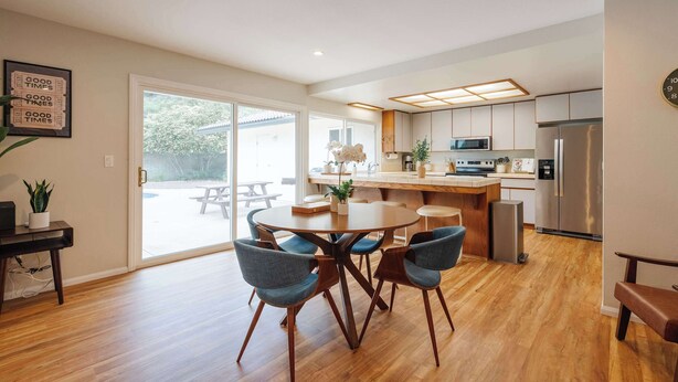 Une cuisine moderne dotée d’un îlot central, de planchers en bois et d’un coin repas avec des chaises bleues.