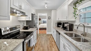 A modern kitchen with white cabinets, a black stove, and granite countertops. - Walk to Downtown Mount Dora! Patio Oasis + King Bed! (Mount Dora)