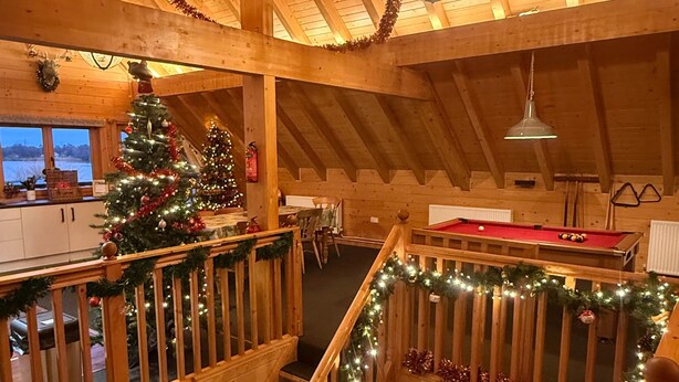 Interior de madera con un árbol de Navidad, una escalera y una mesa de billar.